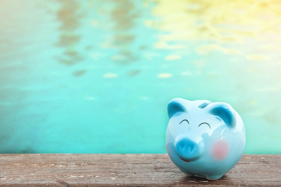 Tirelire bleue posée en bord de piscine, illustrant le coût fiscal d'une piscine en 2026