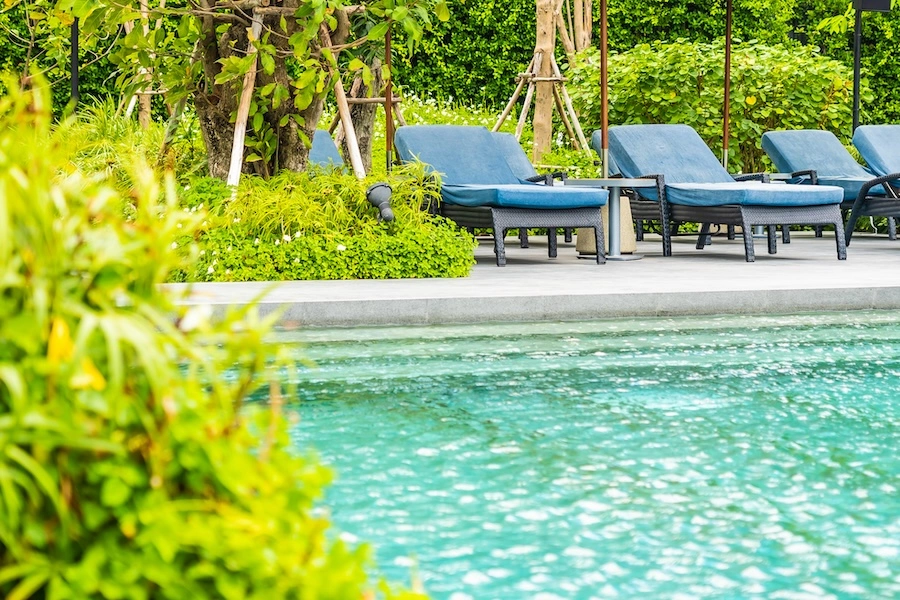 Vue sur une piscine coque 8x4 avec une terrasse et des chaises longues en fond
