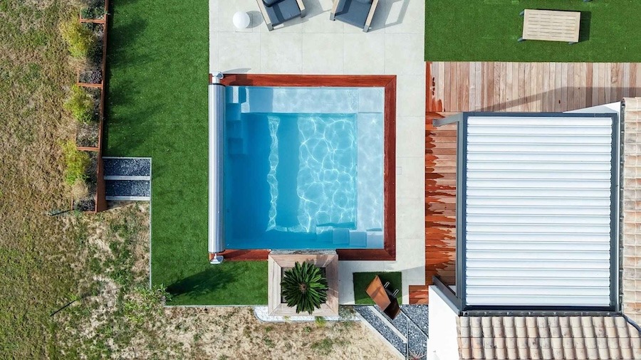 Vue d'en haut d'une piscine coque polyester carrée, intégrée dans un salon de jardin