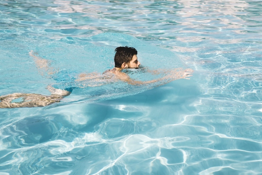 Un adulte nageant dans une piscine coque, illustrant l'importance de la profondeur pour la nage